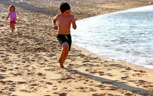 A little boy and a little girl running on the beach